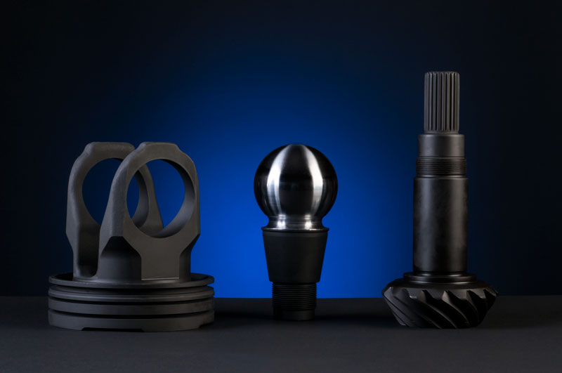 Three automotive parts finshed with a black phosphate coating stand against a glowing blue background.